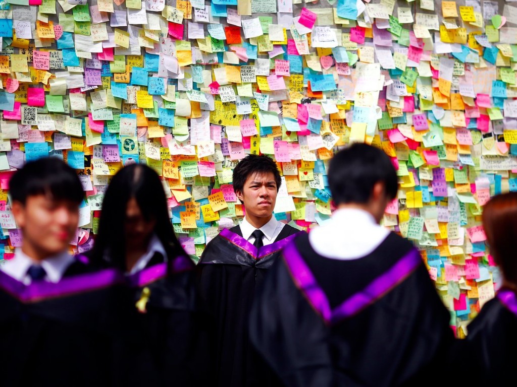Graduated students of Hong Kong Polytechnic University have their pictures taken in front of a wall with messages of support for the pro-democracy movement in the part of Hong Kong's financial central district protesters are occupying October 31, 2014. Reuters/Damir Sagolj