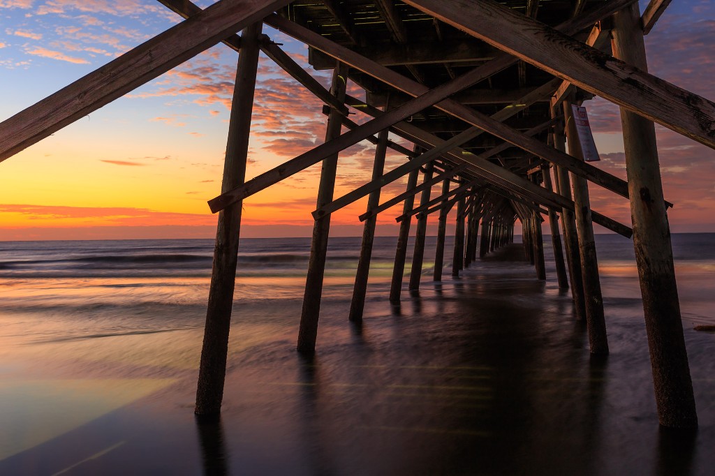 Under the pier of Sunset Beach in Brunswick Island, North Carolina a sunset paints the sky in beautiful colors. Image: Nick Noble