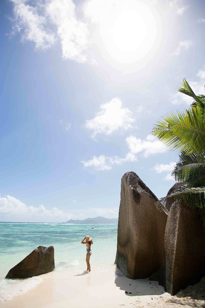 A woman stands in the sun on Anse Source d'Argent beach in La Digue, Seychelles. Image: Lauren Lindsay Hill and Ming Nomchong