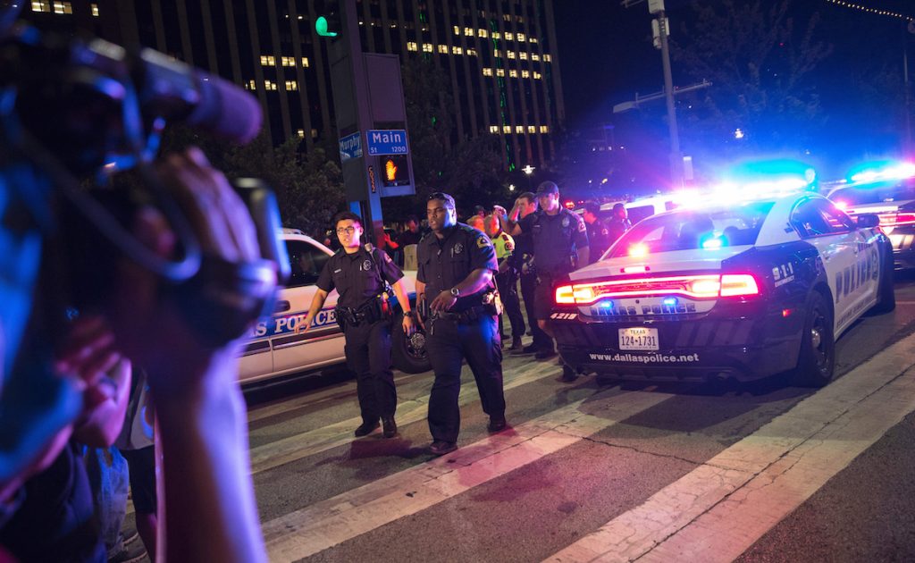 Bystanders stand near pollice baracades following the sniper shooting in Dallas on July 7, 2016. LAURA BUCKMAN/AFP/Getty Images
