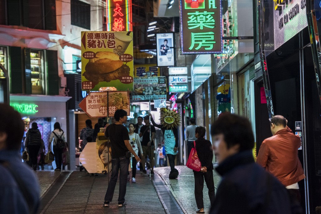 A man holds a sign advertising a restaurant on a street in Macau, China, on Tuesday, Dec. 1, 2015. Macau's casino revenue fell for the 18th straight month in November, as China's moves to curb illicit money flows from the mainland deterred the high-stakes players who rely on junket promoters for betting loans. Photographer: David Paul Morris/Bloomberg via Getty Images
