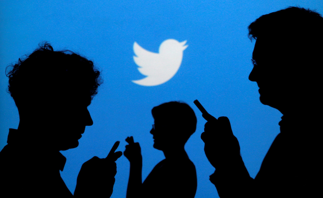 People holding mobile phones are silhouetted against a backdrop projected with the Twitter logo in this illustration picture taken in Warsaw September 27, 2013. REUTERS/Kacper Pempel/Illustration/File Photo