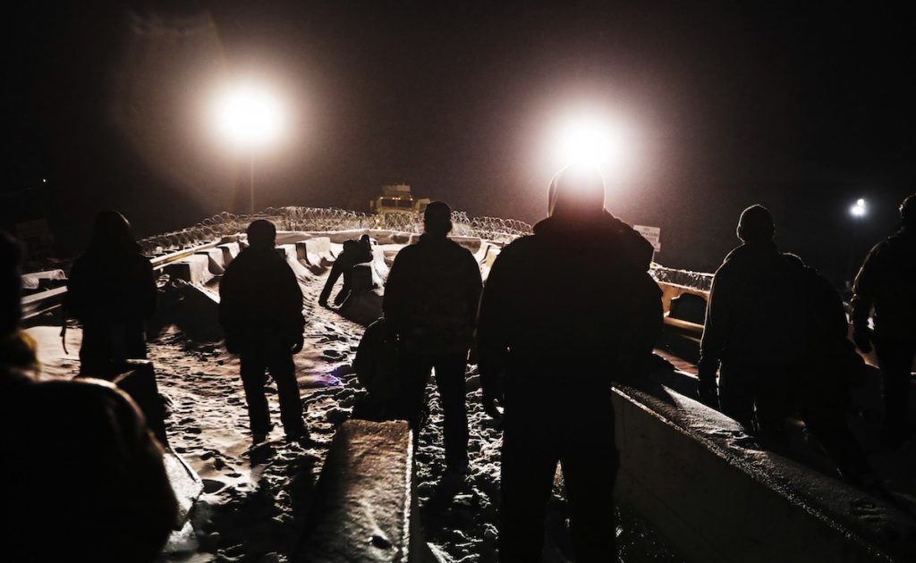 Military veterans walk onto a closed bridge to protest across from police protecting the Dakota Access oil pipeline site in Cannon Ball, N.D. December 1, 2016. AP Photo/David Goldman